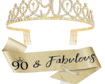 Op de afbeelding: Een goudkleurige tiara met heldere strass-steentjes die "90" spellen en een bijpassende sjerp. De sjerp leest "90 & Fabulous" in zwart schrift. Een decoratieve speld zet de sjerp vast. Perfect voor een 90e verjaardag.