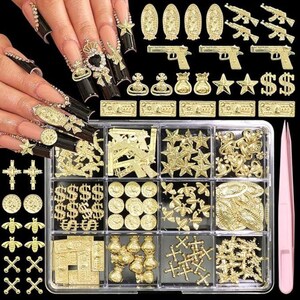 May include: A set of gold-toned metal nail art charms in a clear twelve-compartment plastic organizer box, including shapes of pistols, rifles, dollar signs, stars, bees, crosses, coins, and money bags, accompanied by a pair of pink tweezers.