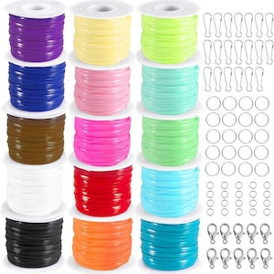May include: A collection of colorful craft supplies, including spools of flat, ribbon-like cord in various colors, along with silver-colored lobster clasps, key rings, and swivel clips. The spools are arranged in rows, showcasing a spectrum of hues.