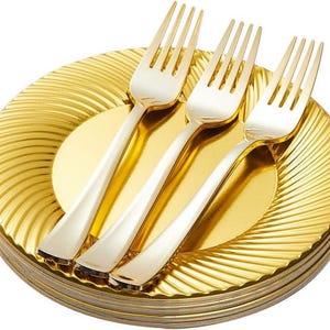 May include: A stack of gold-colored disposable plates with a radial design. Three gold and silver forks are arranged on top. The plates and forks have a shiny, metallic finish, suitable for a party or special event.