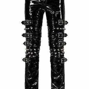 Puede incluir: Pantalones negros de material brillante tipo charol con acabado de alto brillo. Los pantalones incluyen múltiples correas horizontales con hebillas de metal plateado y filas de púas metálicas plateadas a lo largo de las piernas y muslos.