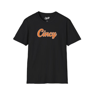 Puede incluir: Camiseta negra con la palabra "Cincy" en letras naranjas.