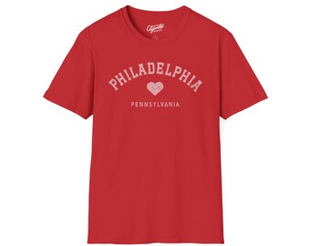 May include: Red t-shirt with the word "Philadelphia" in a distressed, arched font, a heart graphic, and the word "Pennsylvania" below. The shirt has short sleeves and a crew neck.