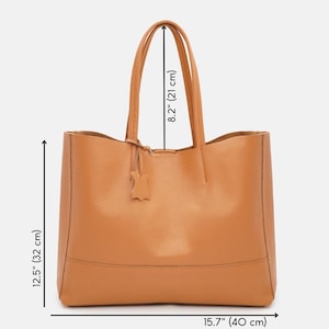 May include: A tan leather tote bag with a rectangular shape. The bag has two handles, each 8.2 inches (21 cm) long, and a small leather tag. The bag is 12.5 inches (32 cm) tall and 15.7 inches (40 cm) wide.