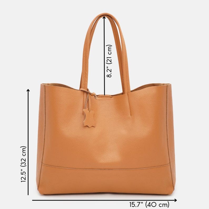 May include: A tan leather tote bag with a rectangular shape. The bag has two handles, each 8.2 inches (21 cm) long, and a small leather tag. The bag is 12.5 inches (32 cm) tall and 15.7 inches (40 cm) wide.