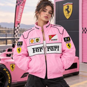 Peut inclure: Une veste de course zippée rose avec le logo Ferrari, des bandes horizontales blanches et divers écussons de sponsors dont Shell, UPS et Bridgestone. La veste possède un col montant, des manches longues et le texte Ferrari en noir sur la poitrine.