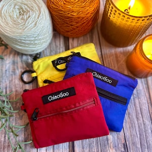 May include: Three small zippered pouches in red, blue and yellow with the text "ChiaoGoo" printed on each. The pouches are made of a nylon fabric and have a zipper closure.