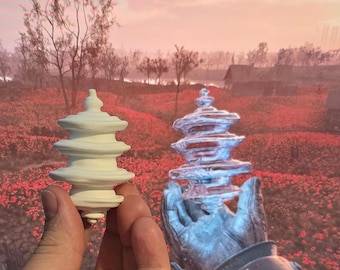 Op de afbeelding: Twee witte keramische pagode-vormige sculpturen, één in een hand en één in een robot hand, tegen een achtergrond van een roze en oranje zonsondergang boven een veld met rode bloemen.