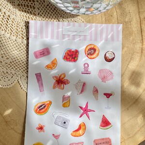 Może przedstawiać: Kolekcja naklejek akwarelowych z letnimi ilustracjami. Naklejki zawierają obrazy owoc&oacute;w, koktajli, aparatu fotograficznego, muszli i teksty "Summer girl" i "Memories". Paleta kolor&oacute;w to gł&oacute;wnie r&oacute;żowy, pomarańczowy i czerwony.