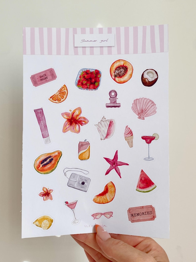 Może przedstawiać: Akwarelowa ilustracja naklejek o tematyce letniej. Zawiera obrazy owoc&oacute;w, koktajli, aparatu fotograficznego i muszli. Tekst "Summer girl" znajduje się na g&oacute;rze. Naklejki są trzymane przez osobę.