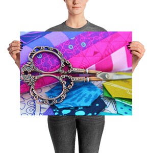 Puede incluir: Un par de tijeras de plata antiguas con detalles ornamentados, descansando sobre un mosaico de telas coloridas de color rosa, morado, azul y verde.