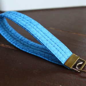 May include: A blue fabric key chain with a geometric pattern and a silver key ring.