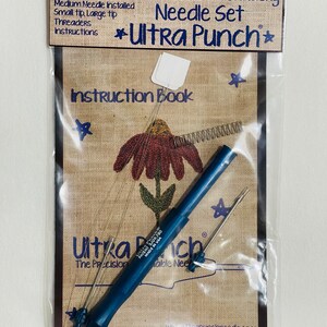 May include: A close-up of a blue punch needle tool with three needles, a spring, and an instruction book. The packaging includes the text "Ultra Punch*" and "Punch Needle Embroidery Needle Set".
