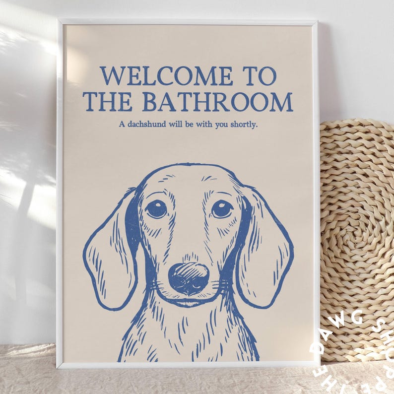 Peut inclure: Une affiche encadr&eacute;e avec une illustration de teckel bleu sur fond beige. Le texte dit "WELCOME TO THE BATHROOM" au-dessus de "A dachshund will be with you shortly."
