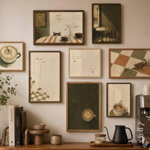 May include: A collection of framed art prints with coffee-themed illustrations, including a latte, a spilled cup, and a cafe scene. The artwork is displayed on a neutral wall above a wooden surface with coffee-making equipment.