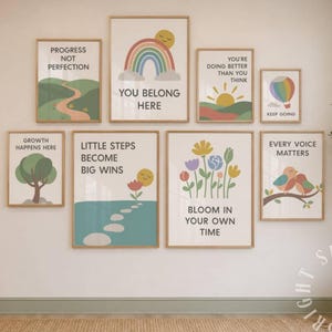 Op de afbeelding: Een galerijwandset van acht ingelijste prints met kleurrijke illustraties van regenbogen, bloemen, vogels en landschappen. Elke print bevat motiverende teksten zoals "You Belong Here", "Growth Happens Here" en "Every Voice Matters".