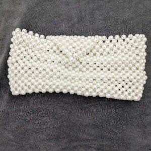 May include: A white pearl headband with a woven design. The headband is made of small, round pearls that are tightly packed together.