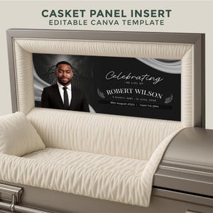 Può includere: Una bara grigia con un inserto nero. L'inserto mostra una foto di un uomo in giacca e cravatta e il testo "Celebrating the Life of Robert Wilson" con date e orari. La bara ha un interno color crema e un cuscino.