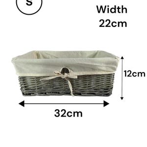May include: A grey wicker basket with a cream fabric lining and a bow. The basket is approximately 12 cm high, 32 cm long, and 22 cm wide. The text "S" is in a circle. The text "Approx Measurements" is below the basket.