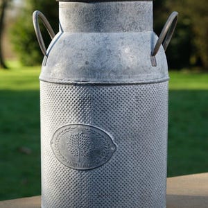 May include: A white ceramic mug with a black handle and the text "But First, Coffee" in a black, handwritten-style font. The mug is on a white surface.