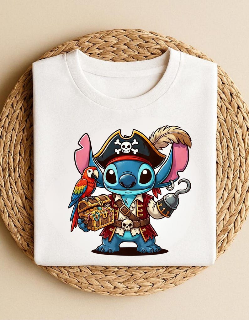 K&ouml;nnte beinhalten: Wei&szlig;es T-Shirt mit einer Cartoon-Figur als Pirat. Die blaue Figur hat gro&szlig;e Ohren, einen Piratenhut mit Totenkopf, eine rote Weste und einen Haken sowie eine Schatzkiste. Ein bunter Papagei sitzt auf der Schulter der Figur.