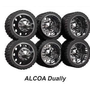 May include: Six black truck tyres with silver rims are stacked in two rows of three. The tyres have a tread pattern for grip. The text "ALCOA Dually" is displayed below the tyres.