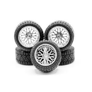 May include: A collection of five miniature black tires with silver rims. The tires have a rugged tread pattern, and the rims feature a complex, multi-spoke design. The wheels are arranged in a slightly staggered formation against a white background.