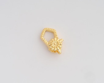 May include: A gold-colored jewelry clasp with a floral design. The clasp has a hexagonal top and a flower-shaped bottom. The metal has a shiny finish, reflecting light. The clasp is likely used for necklaces or bracelets.