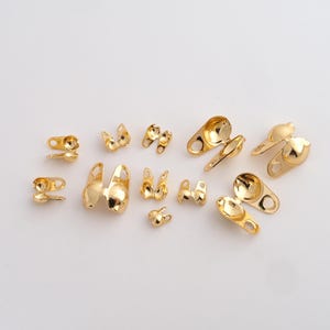 May include: A collection of gold-colored metal clasps and findings, in various shapes and sizes. The clasps include hook and eye closures, and other decorative elements. These jewelry findings are suitable for crafting and jewelry making.