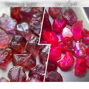 Op de afbeelding: Een verzameling ruwe, gefacetteerde rode edelstenen in een gesplitst beeld. De linkerkant met het label Normal light toont dieprode stenen, terwijl de rechterkant met het label UV LIGHT dezelfde stenen laat zien met een felroze neon gloed.