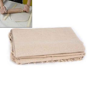 May include: A folded stack of beige linen fabric, suitable for crafts or baking. The fabric has a textured surface and a fringed edge. The image also shows a person using a rolling pin on dough.