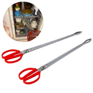 May include: Two long, silver metal tongs with red handles. The tongs have a scissor-like design at the handle end and a rounded tip at the other end. The tongs are designed for handling items in a kiln or oven.