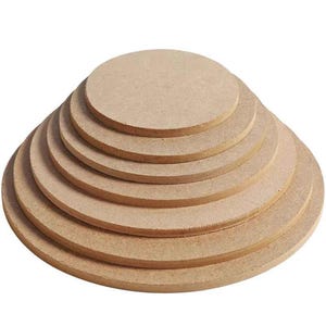 May include: A stack of seven round, unfinished wooden circles of varying sizes. The circles are arranged in a stepped pyramid shape, with the largest circle at the bottom and the smallest at the top. The wood has a light brown color.