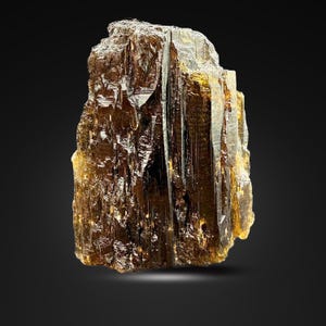 Könnte beinhalten: Ein rohes, bernsteinfarbenes Mineralexemplar mit einer kristallinen Struktur. Das Mineral hat eine raue, strukturierte Oberfläche und eine durchscheinende Qualität. Die Gesamtform ist unregelmäßig, mit scharfen Kanten und einem natürlichen, unpolierten Aussehen.