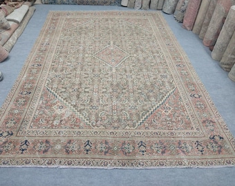 May include: A rectangular area rug featuring a central diamond medallion on a muted taupe field with intricate floral and vine patterns. The border displays a repeating motif in shades of dusty rose, navy blue, and cream, with a fringed edge finish.