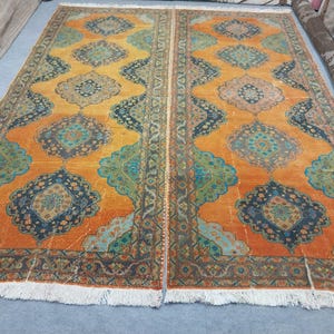 May include: Two matching orange and blue area rugs with intricate geometric patterns. The rugs feature a central medallion design with teal, navy, and orange hues. The rugs have a distressed look and a fringed edge.