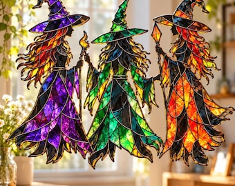 May include: A stained glass suncatcher featuring three figures in pointed hats and flowing robes. The left figure is purple, the center is green, and the right is orange and red. Each figure holds a staff, rendered in vibrant, multi-colored glass.