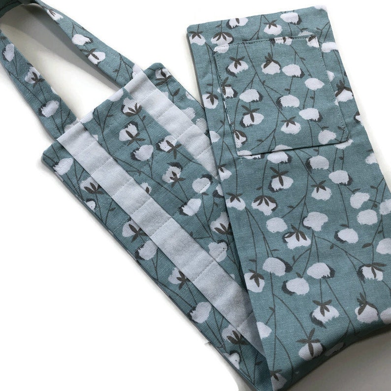 May include: A blue cotton fabric tote bag with a white cotton flower print. The bag has a white velcro closure and a long strap.