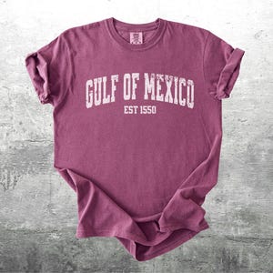 May include: A maroon t-shirt with a white graphic that says "Gulf of Mexico Est 1550".