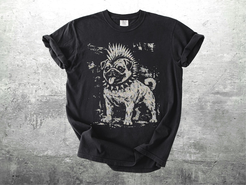 May include: Black t-shirt featuring a distressed graphic of a pug with a mohawk and studded collar. The dog is depicted in a punk rock style, with a tongue sticking out. The shirt is laid flat on a textured surface.