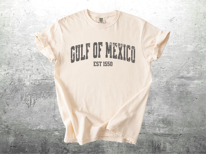 May include: A cream colored t-shirt with a distressed black graphic that reads "GULF OF MEXICO EST 1550".