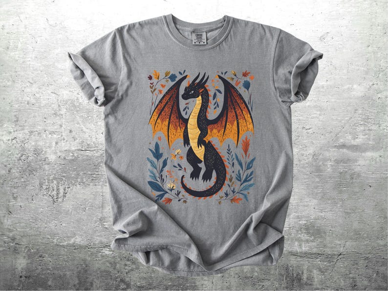 May include: Gray t-shirt with a black dragon illustration with orange and yellow wings. The dragon is surrounded by floral designs in shades of blue, green, and orange.