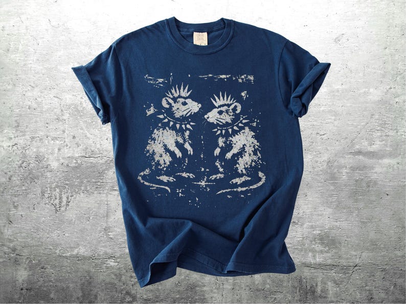 K&ouml;nnte beinhalten: Marineblaues T-Shirt mit einem Used-Look-Motiv von zwei Ratten mit Irokesenschnitt und Nietenhalsb&auml;ndern. Die Ratten blicken sich an. Das T-Shirt hat hochgekrempelte &Auml;rmel und ein Etikett am Ausschnitt.