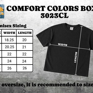 Puede incluir: Una camiseta negra de manga corta etiquetada como Comfort Colors Boxy 3023CL. Una tabla de tallas muestra las medidas de ancho y largo en pulgadas para las tallas S a 2XL, con l&iacute;neas blancas en la camiseta indicando d&oacute;nde se mide el ancho y largo.