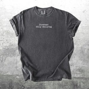 May include: A dark gray t-shirt with the text "forever dilly dallying" printed in white on the front.