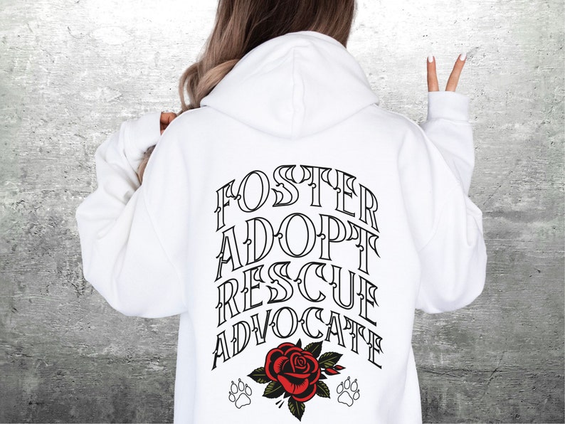 Pu&ograve; includere: Felpa con cappuccio bianca con il testo "FOSTER ADOPT RESCUE ADVOCATE" stampato sul retro. Un rosa rossa con foglie verdi e due impronte di zampa si trovano sotto il testo.