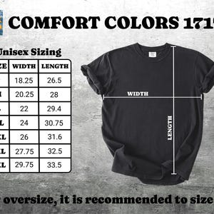 Pu&ograve; includere: Una maglietta nera Comfort Colors 1717 con una tabella delle taglie. La tabella mostra le taglie unisex con misure di larghezza e lunghezza in centimetri, dalla taglia S alla 4XL. &Egrave; visibile anche il testo "Per l'oversize, si consiglia di prendere una taglia in pi&ugrave;".