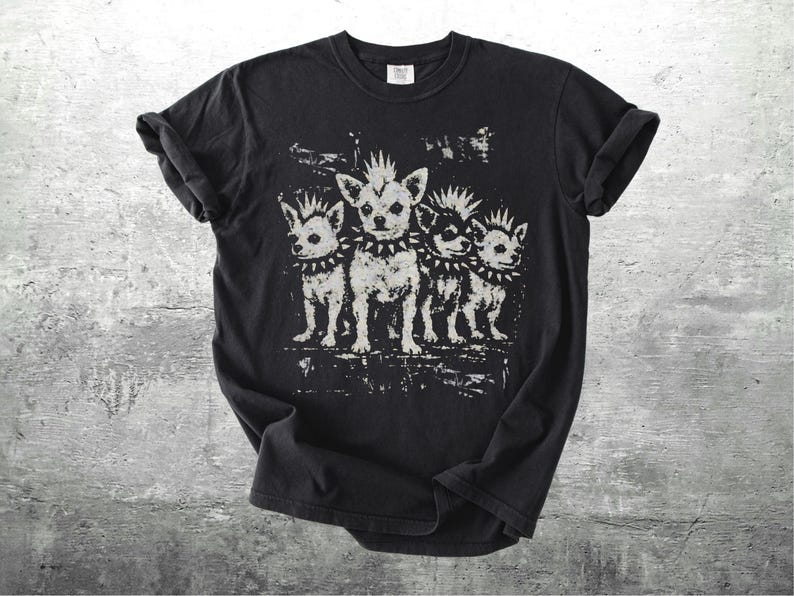 May include: Black t-shirt featuring a distressed graphic of four chihuahua dogs with mohawks and studded collars. The dogs are in a row, with a grunge-style background. The shirt has rolled-up sleeves.