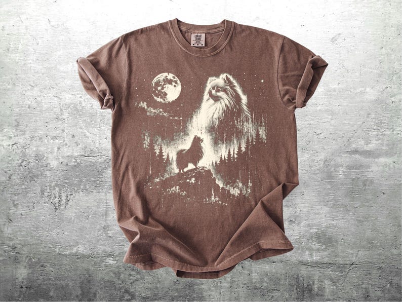 May include: Brown t-shirt featuring a graphic of a Pomeranian dog howling at the moon. The design includes a full moon, trees, and stars, creating a night scene. The shirt has a crew neck and short sleeves.