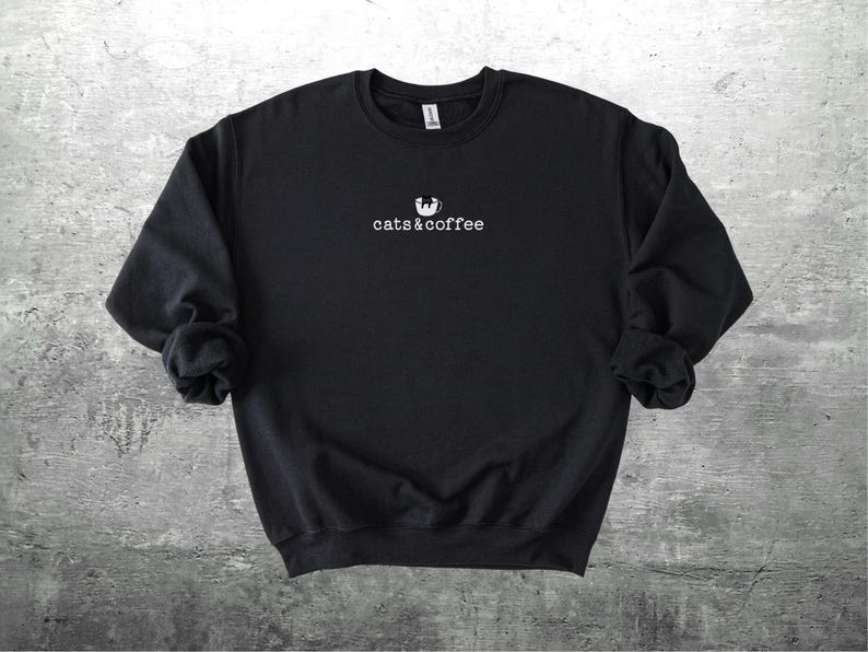 May include: Black sweatshirt with the text "cats & coffee" in white, with a cat silhouette above the text. The sweatshirt is made of a soft material and has long sleeves.